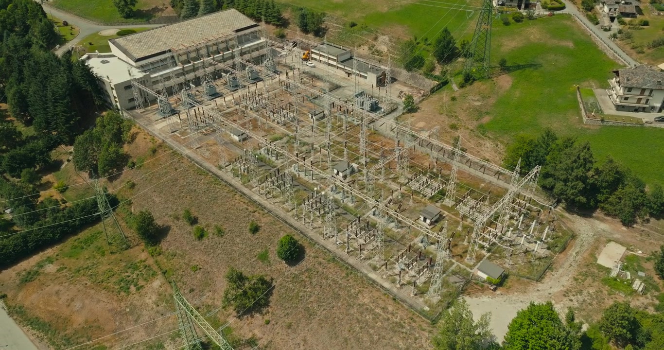 Drone orbits a high-voltage electrical substation where major transmission lines converge, highlighting critical power grid infrastructure supplying electricity across the energy network.