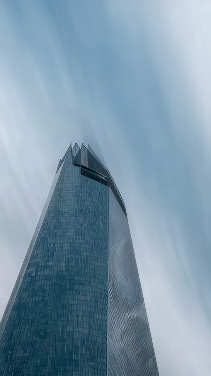 Vertical video: Panning camera revealing tower at base, glass wall and tapered top, showing height