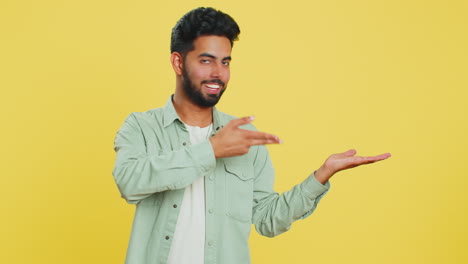 joven mostrando los pulgares hacia arriba y apuntando a la derecha en el espacio en blanco lugar para su logotipo de publicidad