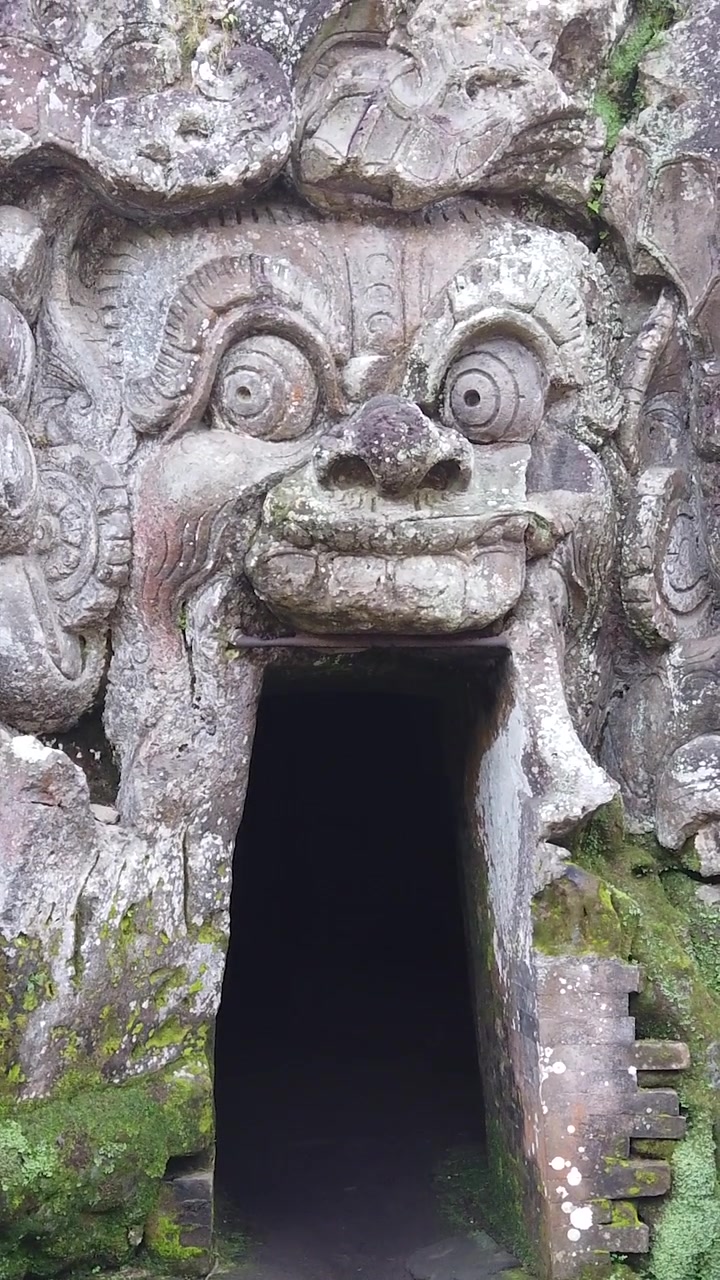 Ingresso del Tempio Goa Gajah con antica scultura in pietra a Ubud, Bali, Indonesia, vista verticale