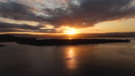 serene lake illawarra at golden hour with calm waters reflecting the vibrant colors of the sunset, aerial dolly with reflection of orange beam