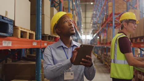 Trabajador-Afroamericano-Con-Casco-Usando-Tableta-En-Almacén