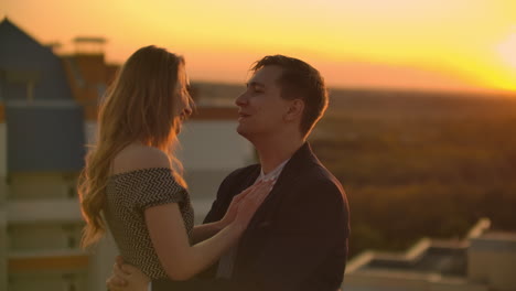 lovely sweet happines couple sit on the roof top with amazing sunset view on the urban city town. they love each other hugs very tenderness sun goes between hair