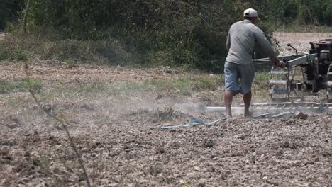 wide exterior static shot of a man ploughing the field in the day