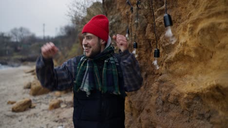 happy man installing string lights on a cliff at the beach
