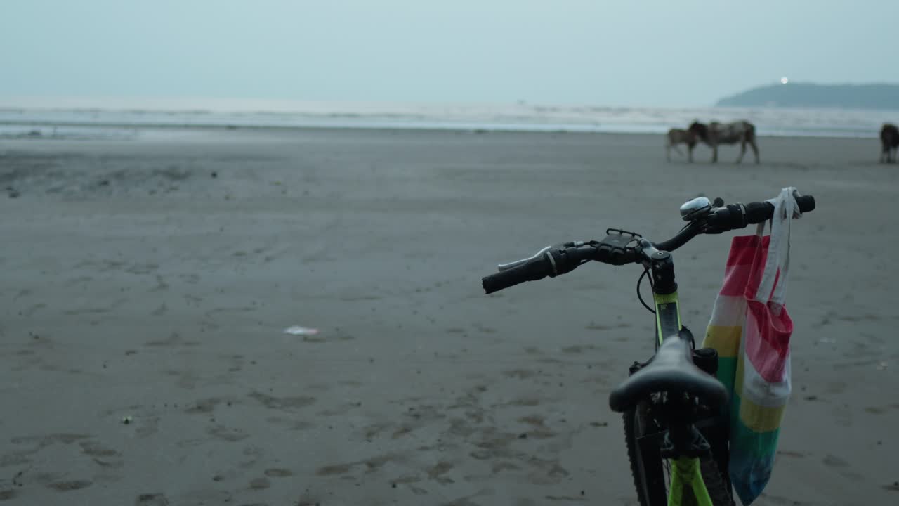 저녁에 해변에서 정적  ⁇ 은 인도에서 파란 시간에 손잡이 주위에 매달린 가방과 함께 서있는 자전거를보고