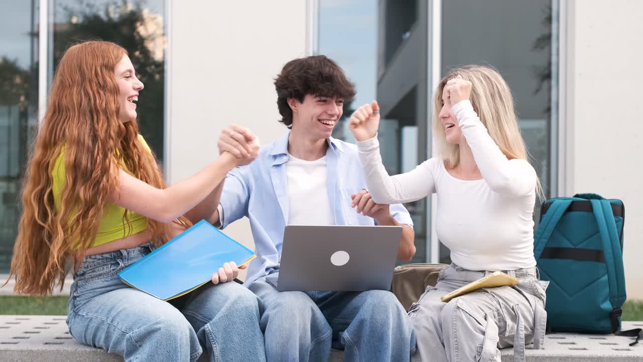University friends celebrating success after checking exam results on laptop