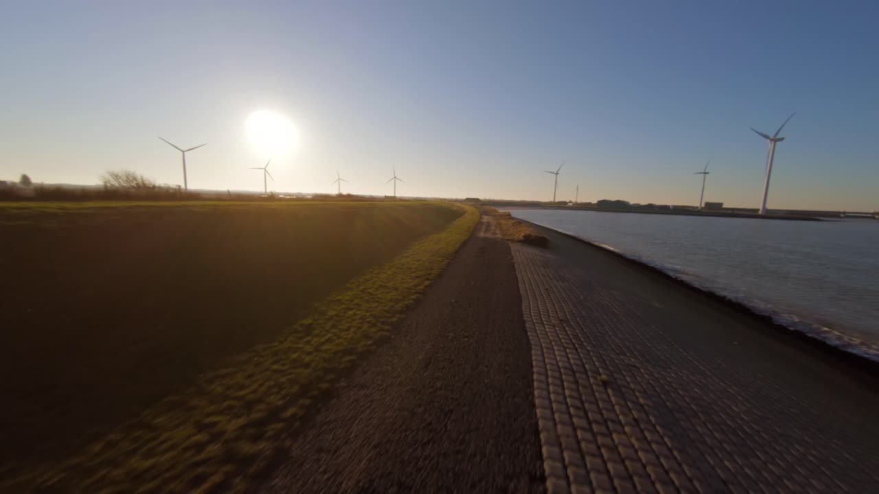 Dutch bicycle path next to the Delta works during sunset. Fast low angle aerial shot