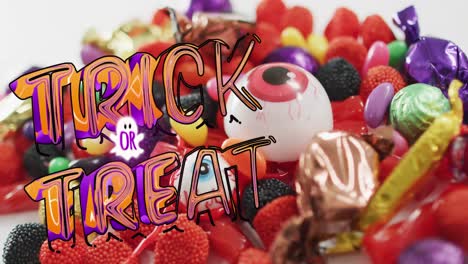 animation of halloween trick or treat text over sweets on grey background