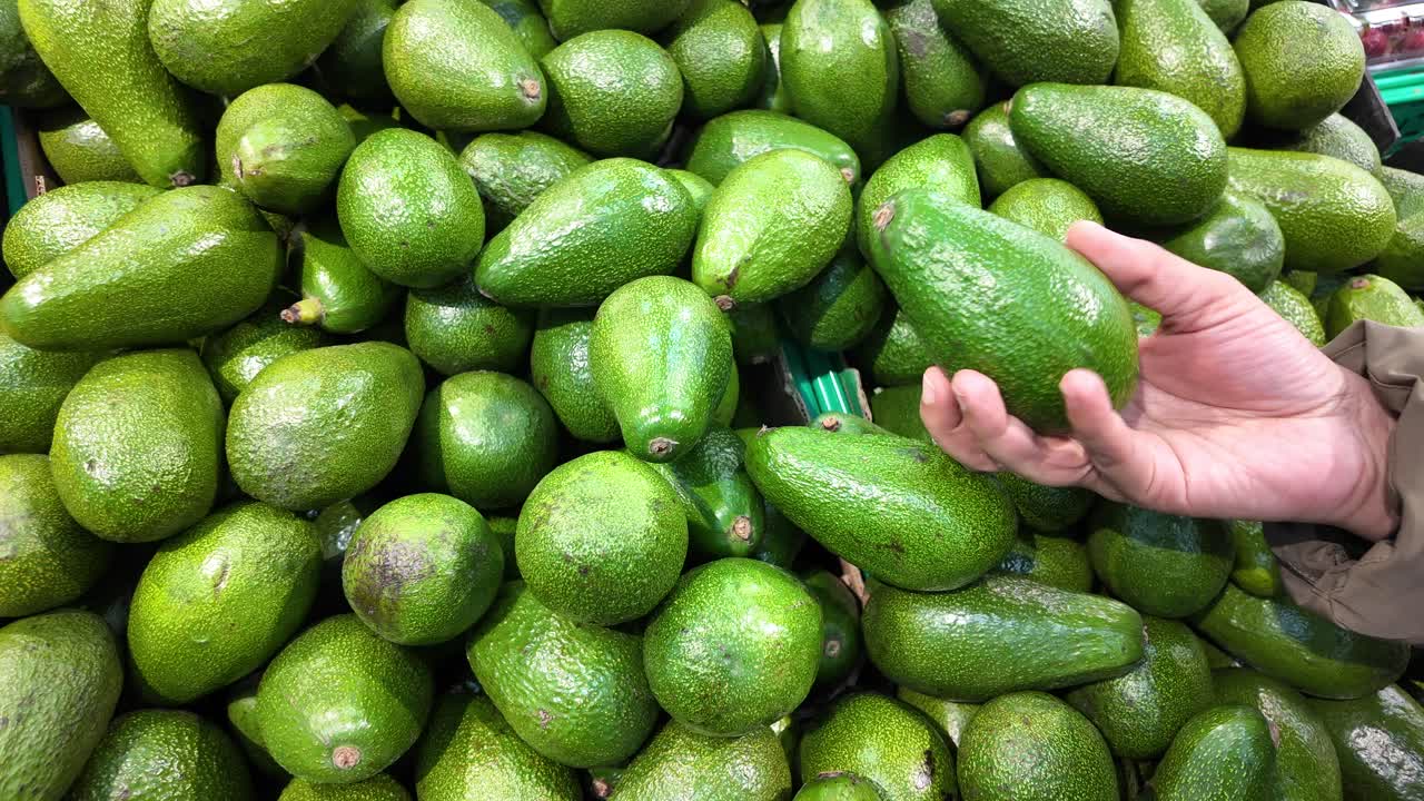 Person holding an avocado in a market