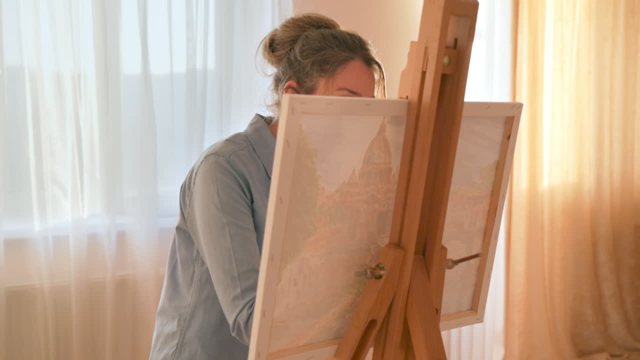 Caucasian woman painting a picture with a palette in her hands, indoors. Slow motion