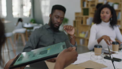 Junge-Afroamerikanische-Geschäftsleute-Treffen-Sich-Beim-Softwareentwicklerteam-Beim-Design-Mobiler-Anwendungen,-Beim-Brainstorming-Beim-Austausch-Kreativer-Ideen-Mithilfe-Eines-Tablet-Computers-Und-Bei-Der-Zusammenarbeit-Im-Startup-Büro