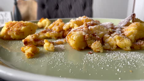 Zeitlupen-Nahaufnahme-Des-Bestreuens-Des-Traditionellen-österreichischen-Pfannkuchens-Kaiserschmarrn-Mit-Puderzucker