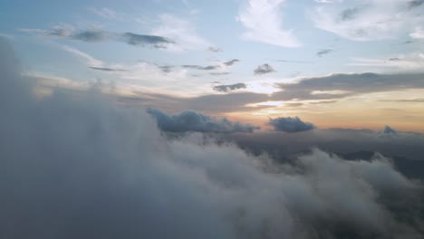 4k drone flight through fluffy white cloud with colorful sunset in sky