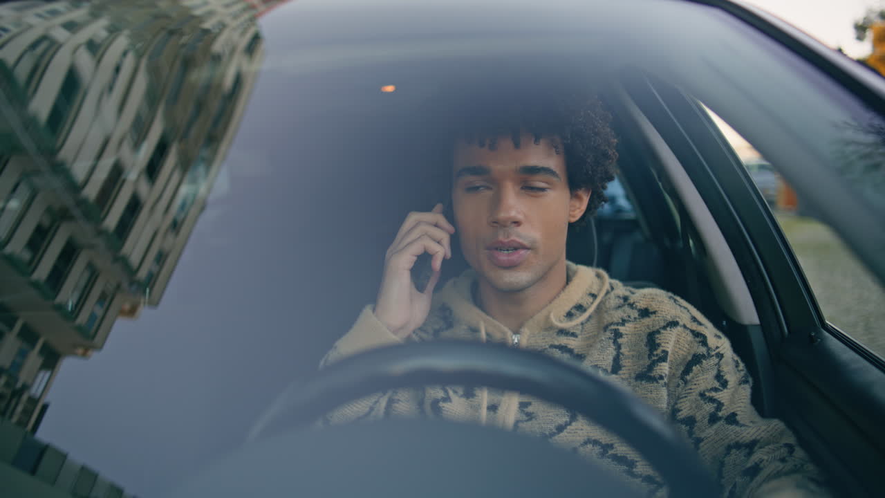 Focused driver talking cellphone inside car closeup. Latin american guy calling