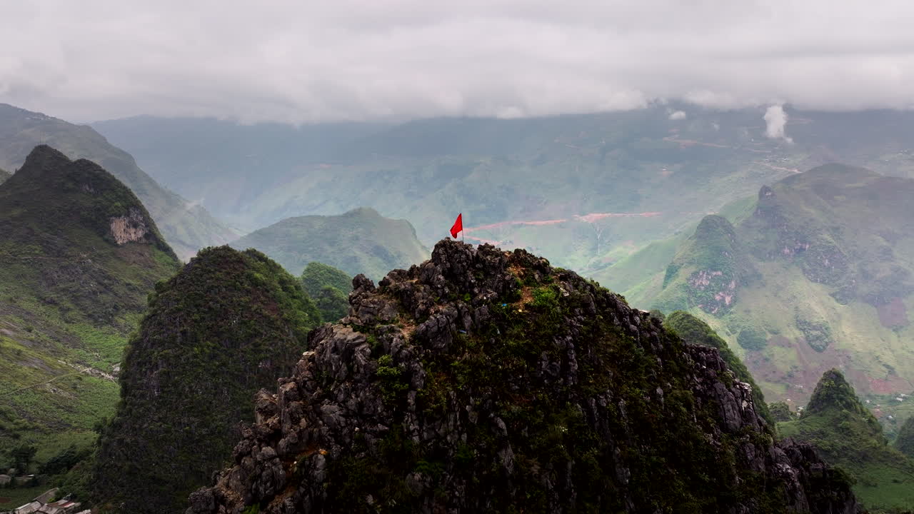 Vietnam Flag on top of mountain with landscape in background. Aerial backward
