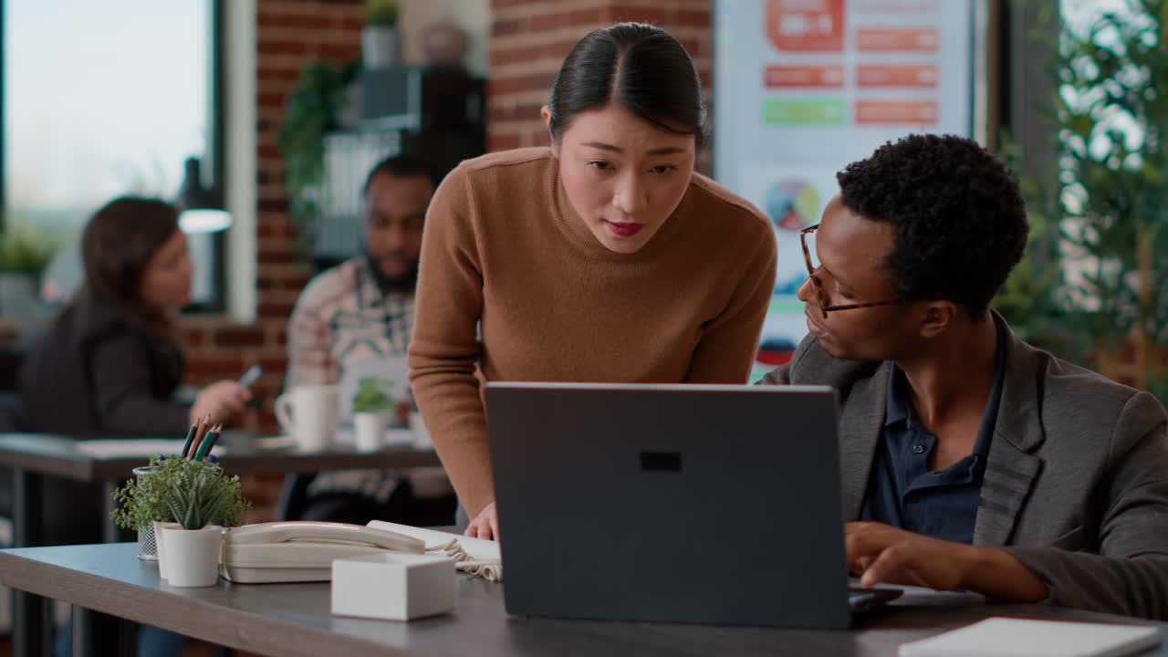 Business people looking at documents charts and laptop