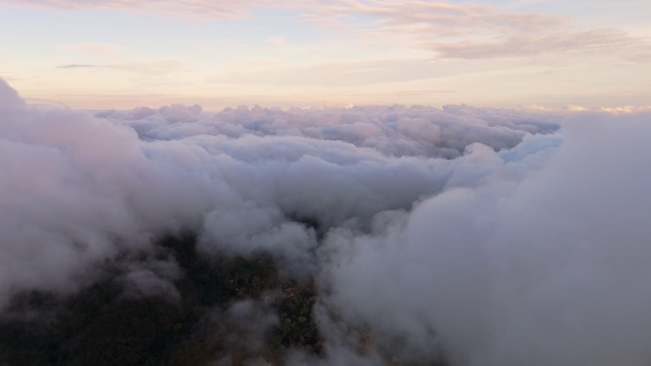 Cinematic flight above a dense sea of clouds featuring soft pink and purple hues. A majestic sunrise cloudscape over the highlands of Marilog District, Davao, creating a heavenly atmosphere