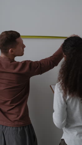 couple measuring wall for home improvement project