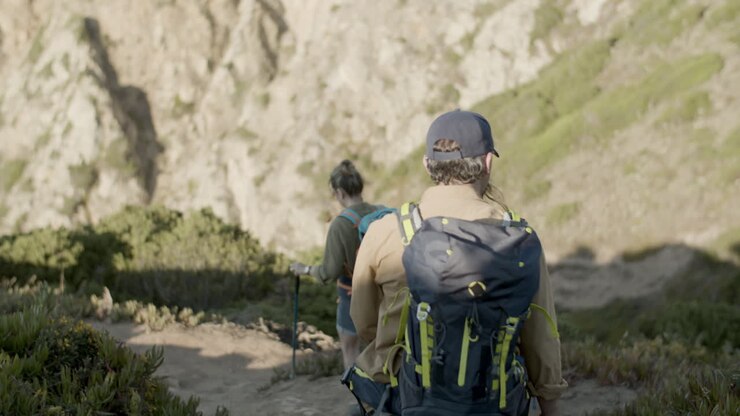 Back view of a Caucasian family descending steep mountain slope hiking