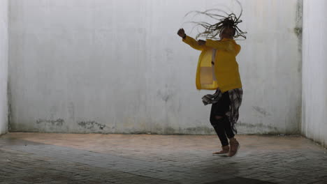 Mujer-Bailando-Joven-Bailarina-Callejera-De-Raza-Mixta-Realizando-Movimientos-De-Hip-Hop-De-Estilo-Libre-Disfrutando-De-La-Expresión-De-Danza-Moderna-Practicando-En-Un-Almacén-Sucio-Con-Chaqueta-Amarilla