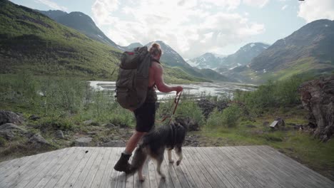 一名白人徒步旅行者和他的狗在步道上休息,欣赏挪威林斯达伦山谷的景色 - - 宽<unk>镜头