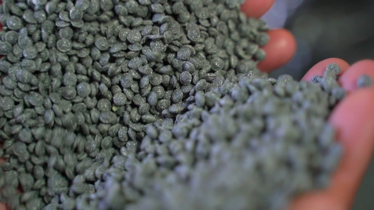 손을 통해 실행되는 회색 재활용 플라스틱 알갱이의 영화 샷