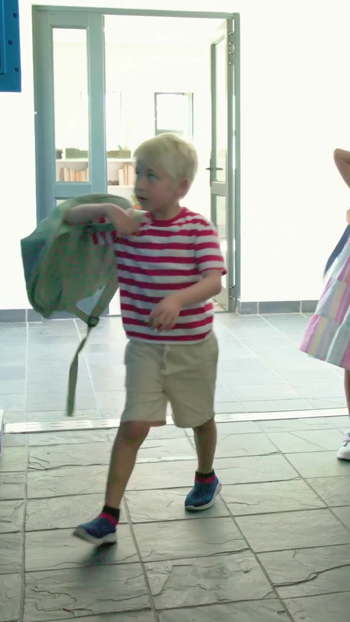 Vertical video: Girls moving aside boy striped T opening locker pulling backpack leaving at school