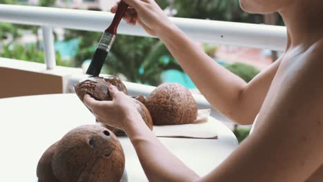 young female crafting coconut shells on balcony at home