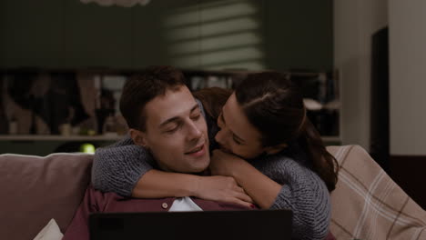 couple hugging and watching laptop