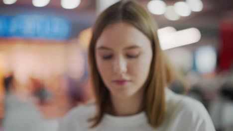 close-up of thoughtful young woman with soft expression, slightly blurred focus, set against colorful blurred background with vibrant lights creating a serene and introspective mood