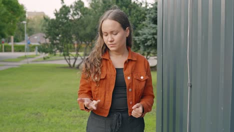 mujer joven de pie y contando algo en los dedos, vista frontal