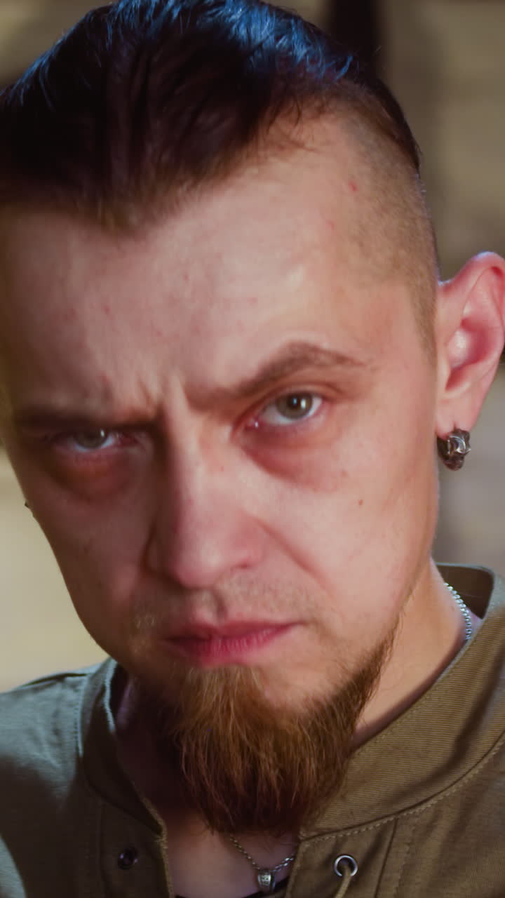 hombre pensativo en una taberna medieval en primer plano. huésped dudoso con barba levanta la ceja tomando decisiones en el pub. reconstrucción histórica y juego de rol