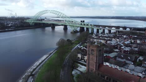 aerial descent over widnes small town jubilee bridge church rooftops neighbourhood north west england