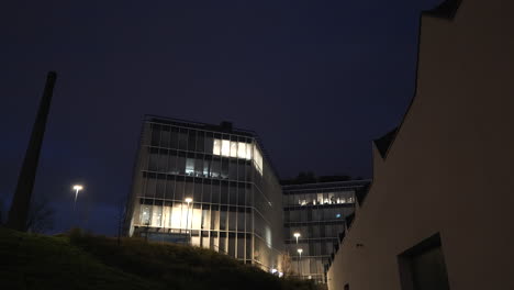 Nuevo-Edificio-De-Oficinas-Al-Lado-De-Una-Chimenea-Filmada-Temprano-En-La-Mañana-En-La-Oscuridad