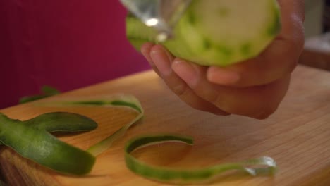 pelar un pepino con un pelador en una tabla para cortar