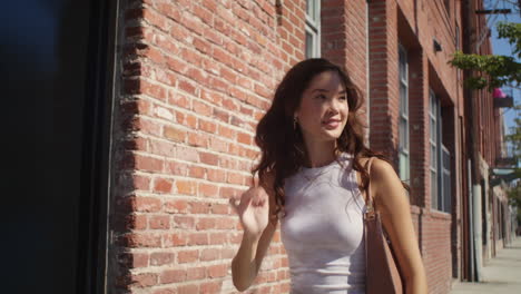 Smiling-girl-walking-near-brick-wall-closeup.-Asian-pretty-lady-going-on-street.