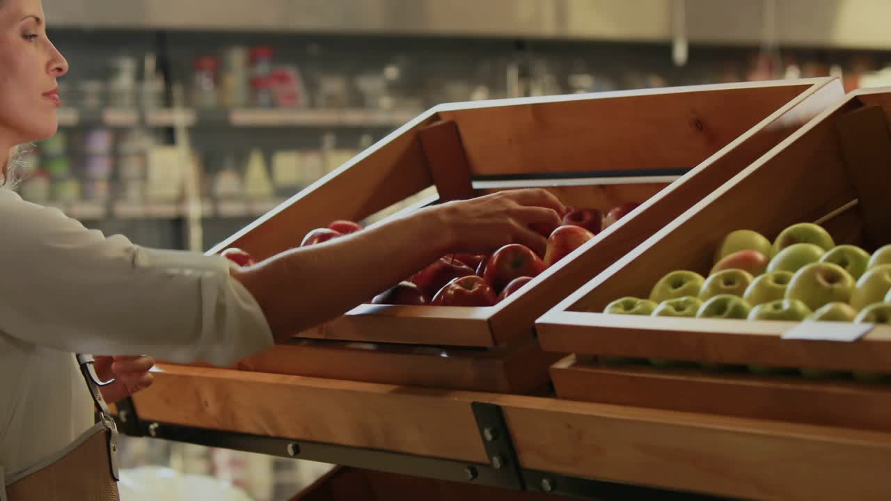 Shopper reaching into produce bin, selecting, smelling, choosing, buying apples with HUD guiding