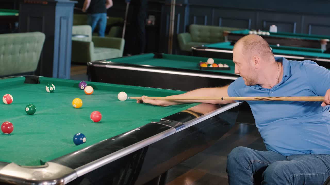 Adult men with disabilities in a wheelchair play billiards in the club