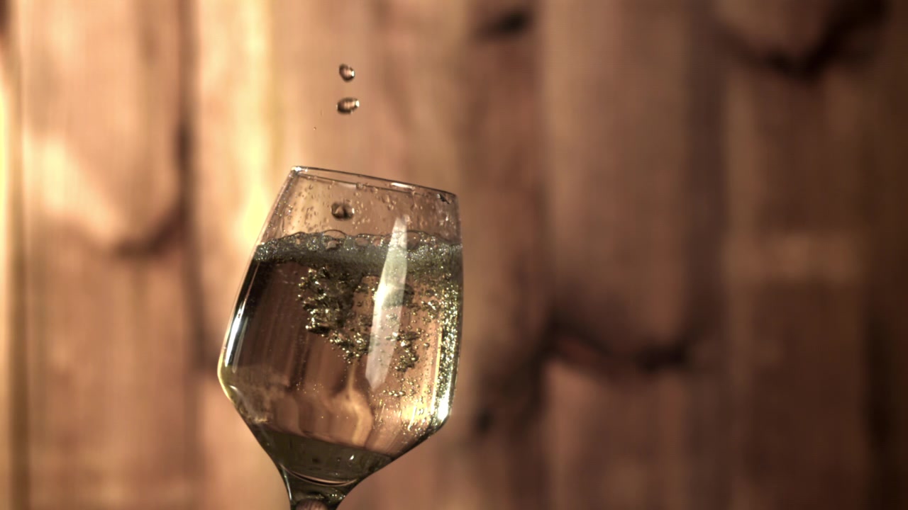 Goccioline d'acqua in slow motion che schizzano in un calice da vino