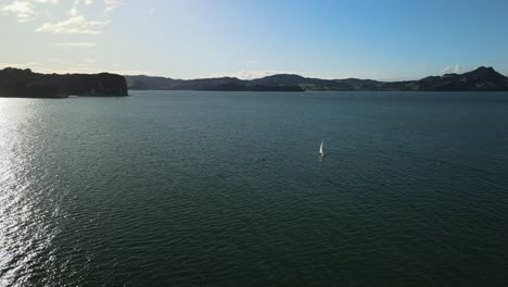 Vuelo-Cinematográfico-Alrededor-Del-Yate-De-Vela-Al-Atardecer-Con-Una-Manada-De-Delfines-Chapoteando-Detrás