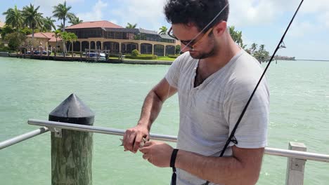 man unhooks small mangrove snapper on fishing rod