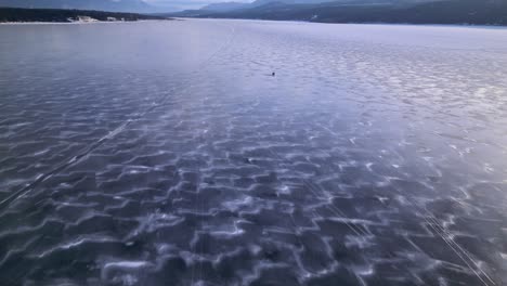 A-truck-is-followed-along-a-frozen-lake-in-the-mountians