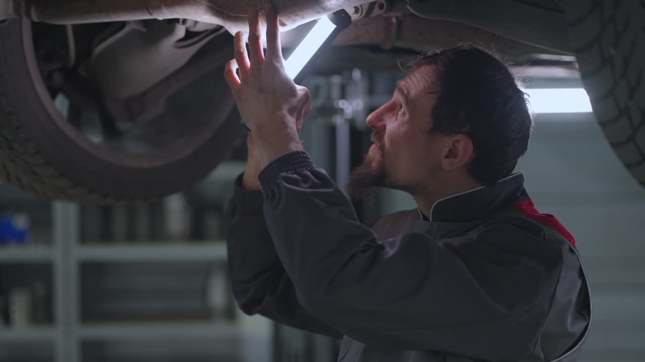 남자 오토 메카닉은 자동차  ⁇ 을 쳐다보고 엘리베이터에 올라 서서히 작동하는 오작동을 찾습니다.
