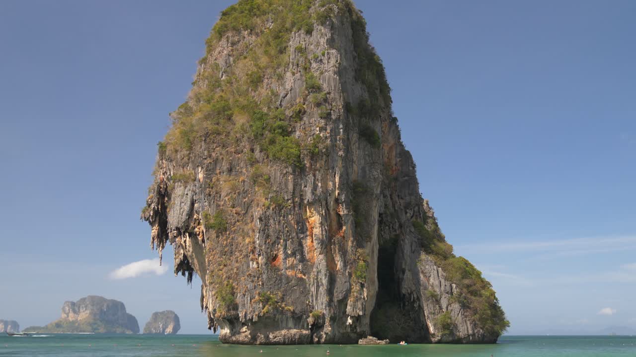 Tall limestone cliff towering over the turquoise waters of Railay Beach, Krabi