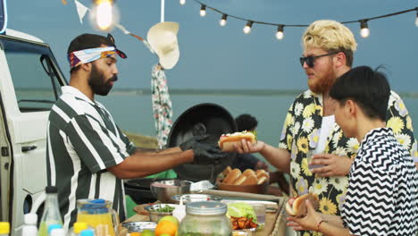 food truck seller giving hot dog to customers at summer festival