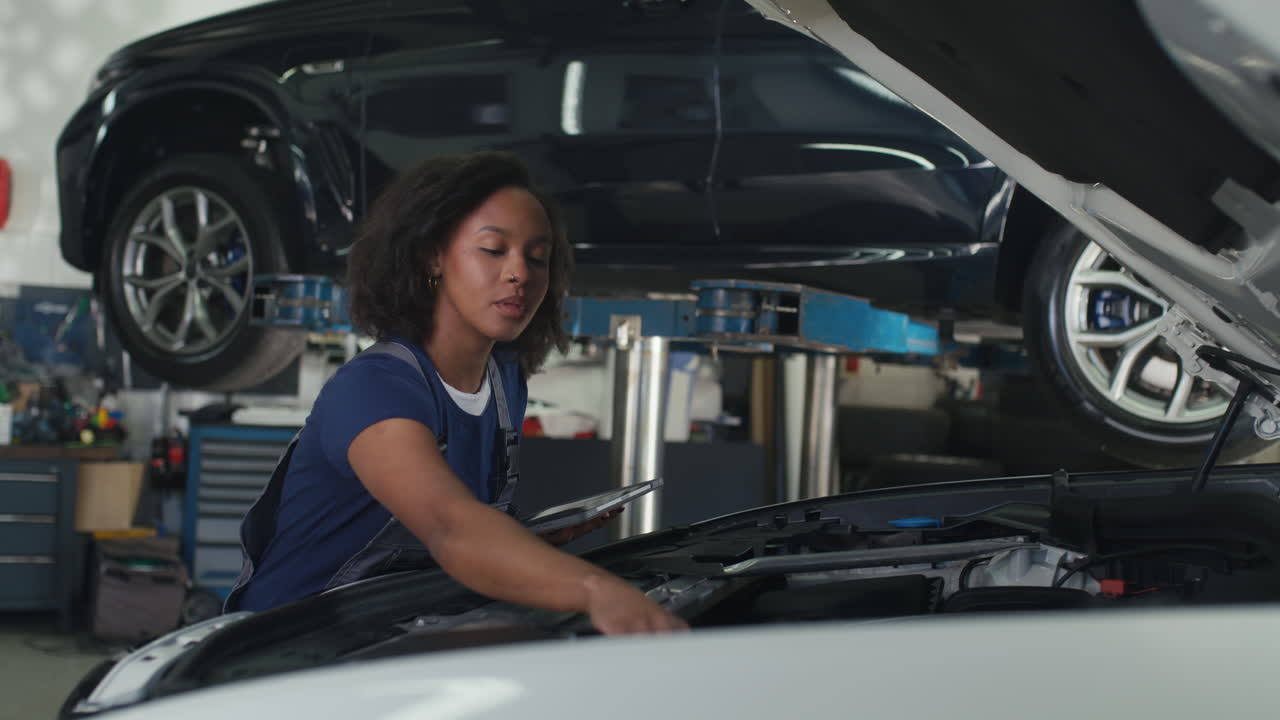 Maintenance of modern vehicles in a successful auto repair shop a woman mechanic using a digital