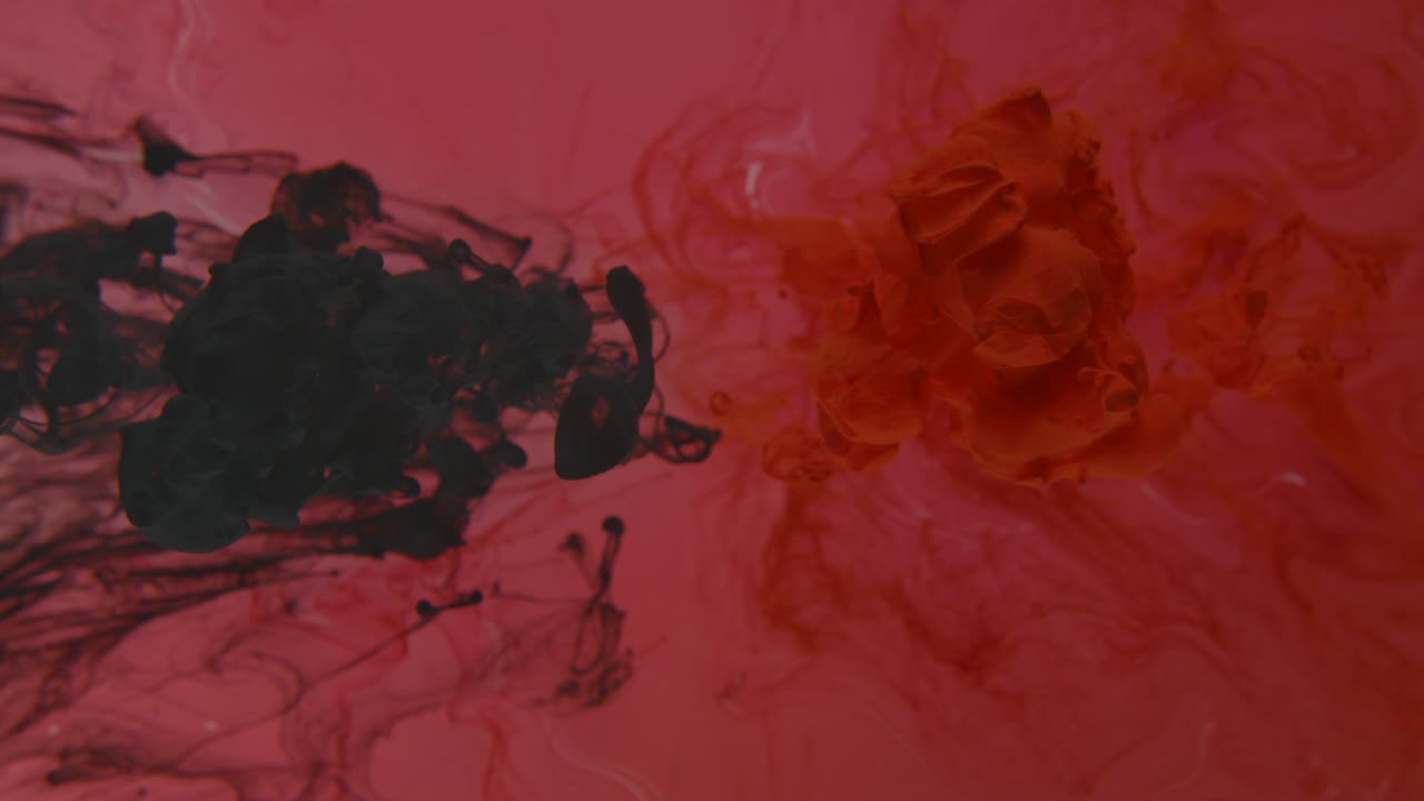 fotografía de estudio en cámara lenta de tinta roja y negra disolviéndose en el agua - fondo