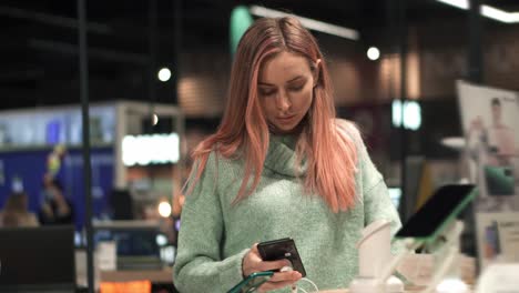 female customer is taking mobile phone from counter and testing it