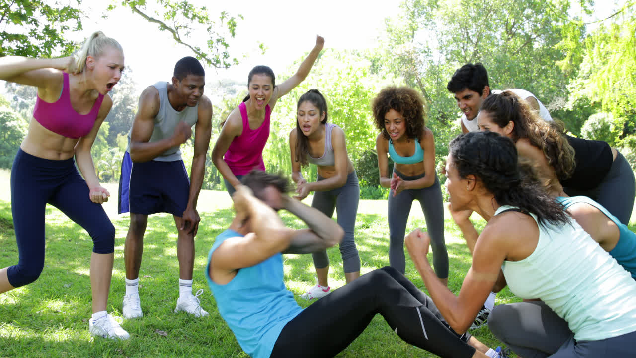 grupo de fitness animando a un hombre haciendo abdominales